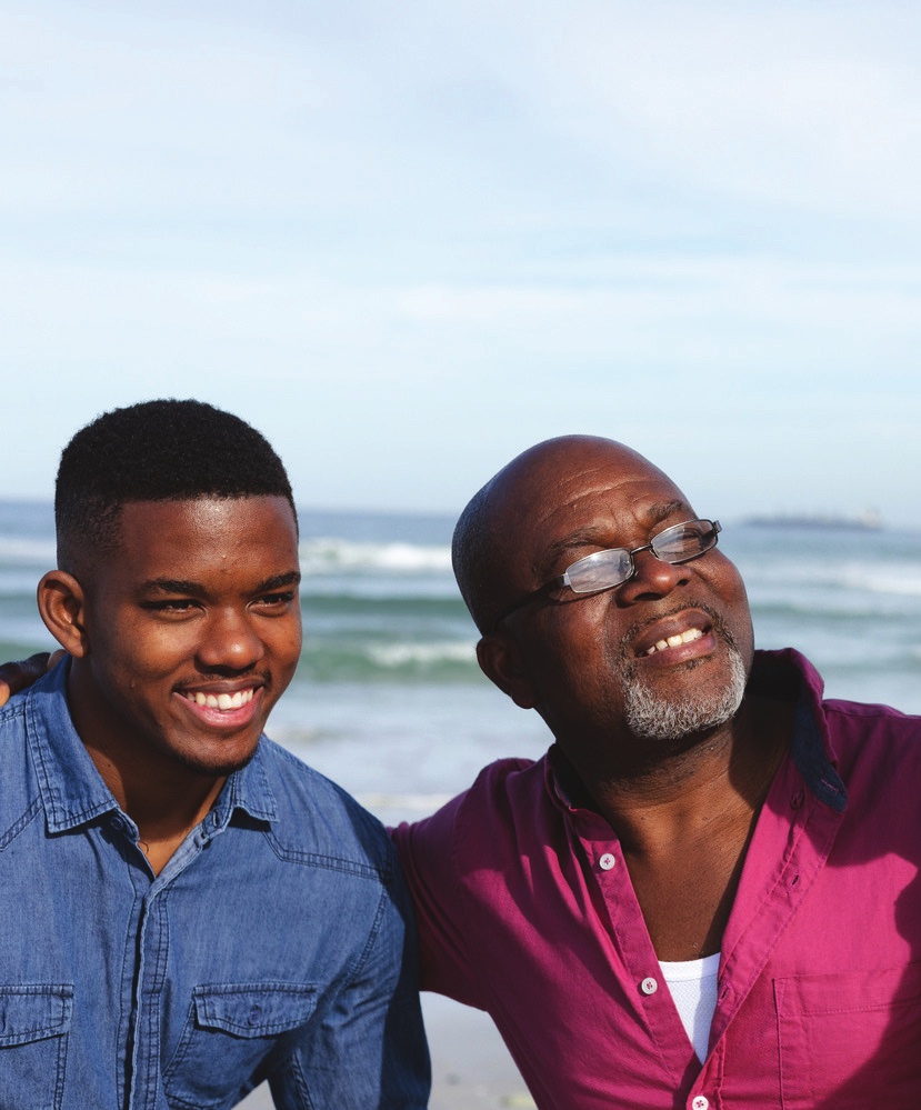 A father and his teenage son smiling at the beach