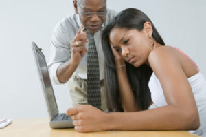 Male teacher instructing his student sitting in front of a laptop