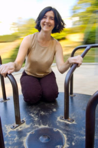 Smiling young woman enjoys a spin on a merry-go-round, background is a blur of motion.