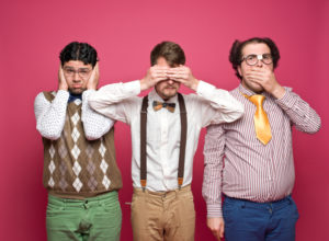 Three nerd student standing over pink background and posed in hear, see and speak no evil poses. Horizontal shot.