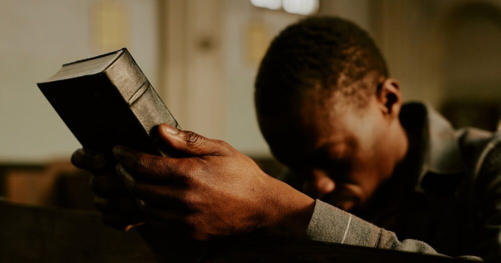 black man praying Bible Christian